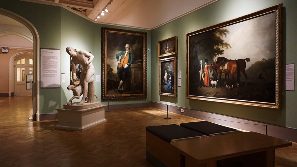 pexels-photo-3004909 An elegant art gallery room featuring classical paintings and a prominent marble statue.